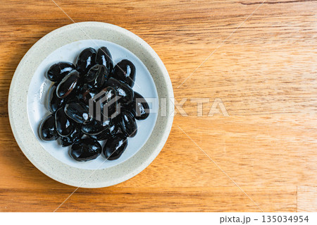 木目テーブルの上の小皿に盛られた黒豆 135034954