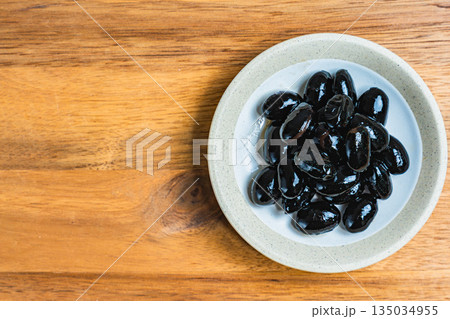 木目テーブルの上の小皿に盛られた黒豆 木目テーブルの上の小皿に盛られた黒豆 135034955