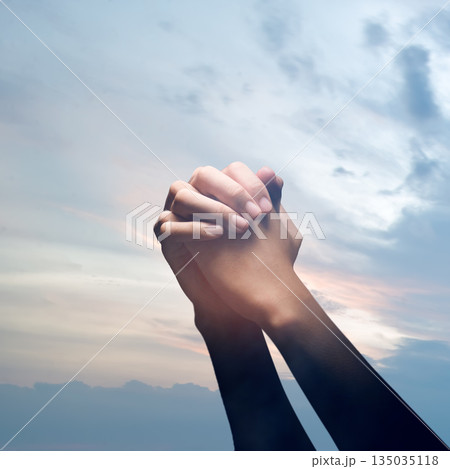 Closeup image of hands clasped together in prayer against a backdrop of a peaceful and soft colored sky. Concept of faith, hope, and spirituality Closeup image of hands clasped together in prayer against a backdrop of a peaceful and soft colored sky. Concept of faith, hope, and spirituality 135035118