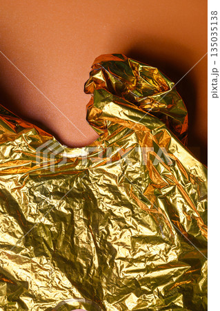 Closeup of crumpled golden foil texture against a solid orange background. Mockup or Copy space. Great for use as backgrounds, overlays, or design elements in various creative projects 135035138