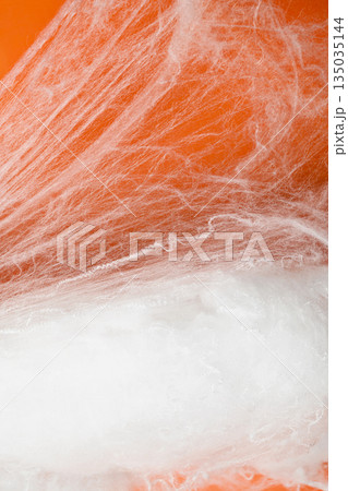 Spooky Halloween decoration with white cobweb on an orange background. Mockup, copy space, or template. Perfect for creating a festive atmosphere for Halloween parties or spooky projects 135035144