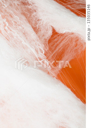 Spooky Halloween decoration with white cobweb on an orange background. Mockup, copy space, or template. Perfect for creating a festive atmosphere for Halloween parties or spooky projects 135035146