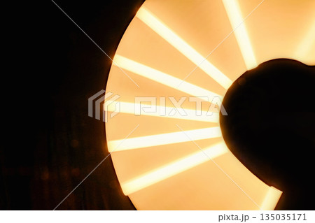 Closeup view of a glowing, orange disk with radial, illuminated stripes against a dark background. The light creates an abstract and modern aesthetic Closeup view of a glowing, orange disk with radial, illuminated stripes against a dark background. The light creates an abstract and modern aesthetic 135035171