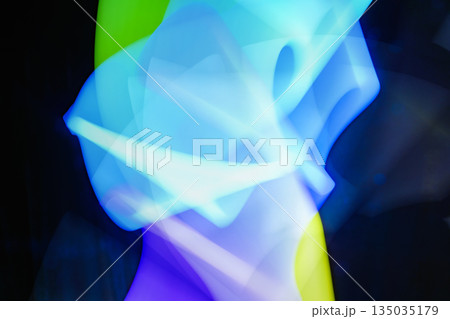 Abstract light painting featuring dynamic and vibrant color streaks in shades of blue, green, and purple against a dark background. The movement through blurred, flowing lines of light 135035179