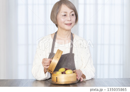 せいろでさつまいもを蒸して食べるシニア女性 せいろでさつまいもを蒸して食べるシニア女性 135035865