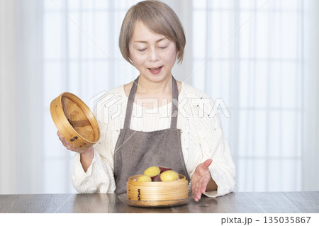せいろでさつまいもを蒸して食べるシニア女性 せいろでさつまいもを蒸して食べるシニア女性 135035867