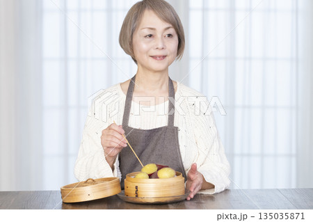 せいろでさつまいもを蒸して食べるシニア女性 せいろでさつまいもを蒸して食べるシニア女性 135035871