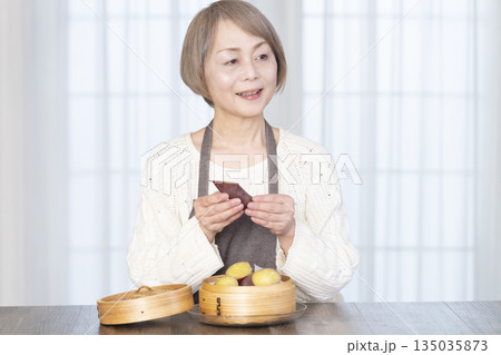 せいろでさつまいもを蒸して食べるシニア女性 せいろでさつまいもを蒸して食べるシニア女性 135035873