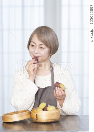 せいろでさつまいもを蒸して食べるシニア女性 せいろでさつまいもを蒸して食べるシニア女性 135035897