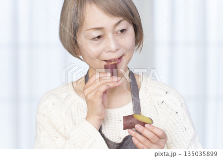 せいろでさつまいもを蒸して食べるシニア女性 せいろでさつまいもを蒸して食べるシニア女性 135035899