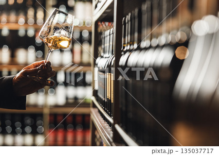 Professional Sommelier Evaluating White Wine in Cellar Shop Environment 135037717