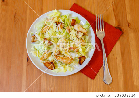Fresh healthy caesar salad with chicken breast, lettuce, parmesan cheese, dressing and croutons on wooden table. Top view 135038514