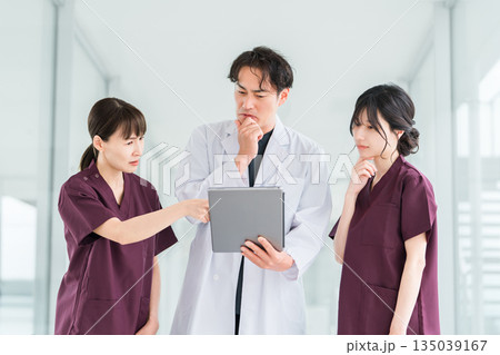 病院の通路で話す医者・医師・看護師・医療従事者・ドクター・作業療法士・理学療法士の男女 病院の通路で話す医者・医師・看護師・医療従事者・ドクター・作業療法士・理学療法士の男女 135039167