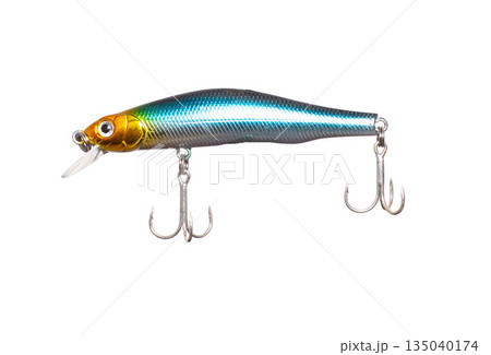 Metallic fishing lure isolated on white background. Hard bait minnow with shiny blue-green body, gold head, diving lip, and two treble hooks. 135040174