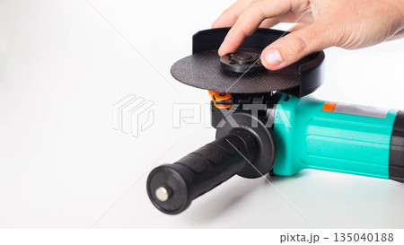 Close-up of hand tightening a nut to hold a cutting disc in an angle grinder. Safety precautions. Copy space for text, industry 135040188