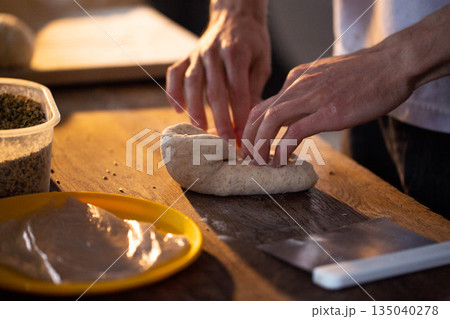 Person hands kneading bread dough on wooden surface preparing homemade baked food close up detail of culinary process home cooking baking food preparation Person hands kneading bread dough on wooden surface preparing homemade baked food close up detail of culinary process home cooking baking food preparation 135040278