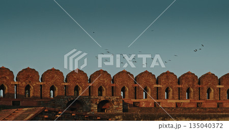 Red Fort crenellated brick wall with domed bastions and traditional military defensive architecture Red Fort crenellated brick wall with domed bastions and traditional military defensive architecture 135040372
