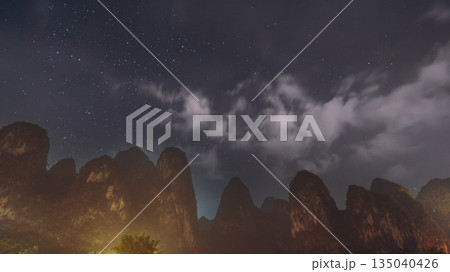 Yangshuo karst mountains silhouette under starry night sky and Milky Way clouds Yangshuo karst mountains silhouette under starry night sky and Milky Way clouds 135040426
