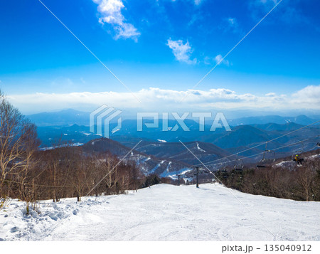 快晴の空の下に広がる冬のスキー場コースと遠くに連なる山並みの展望 (群馬県、川場) 快晴の空の下に広がる冬のスキー場コースと遠くに連なる山並みの展望 (群馬県、川場) 135040912