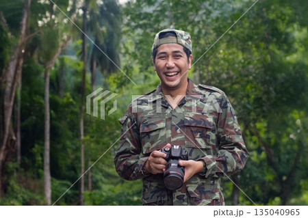 Asian man in a military uniform is capturing the beauty of nature with a DSLR camera 135040965