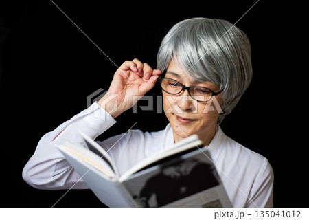 老眼鏡で読書をする白髪のシニア女性 老眼鏡で読書をする白髪のシニア女性 135041012