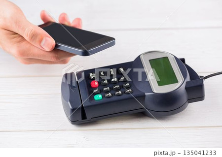 Flat design is showing smartphone tapping payment terminal on white tabletop, contactless payment Flat design is showing smartphone tapping payment terminal on white tabletop, contactless payment 135041233