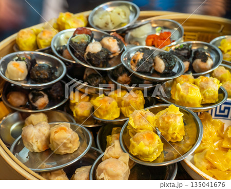 Delicate pork shumai, artfully arranged in a small bowl, ready to serve from a traditional bamboo steamer in an authentic Asian kitchen setting 135041676