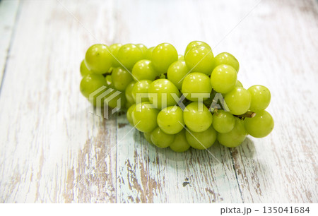 Vibrant green Shine Muscat grapes on old wood background, perfect for showcasing vitamin-rich healthy food 135041684