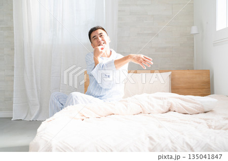 起きてベッドの上でストレッチをする男性 起きてベッドの上でストレッチをする男性 135041847