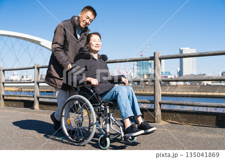 車椅子を押して散策する熟年夫婦 135041869