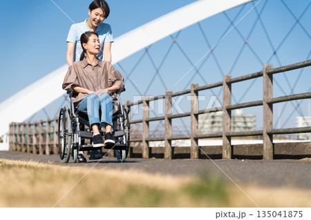 車椅子を押して散策する女性と介護士 車椅子を押して散策する女性と介護士 135041875
