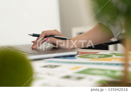 A diverse business team analyzing environmental charts and graphs in a collaborative meeting to create sustainable strategies in a modern office. 135042018