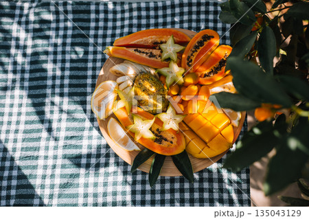 Colorful tropical fruit platter enjoyed in a garden setting on a sunny day Colorful tropical fruit platter enjoyed in a garden setting on a sunny day 135043129