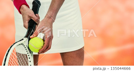 Midsection of sportswoman holding tennis racket Midsection of sportswoman holding tennis racket 135044666