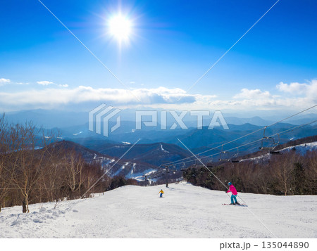 太陽が眩しく輝く冬のスキー場の高所から山並みを見渡す非圧雪コースの風景 (群馬県、川場) 135044890