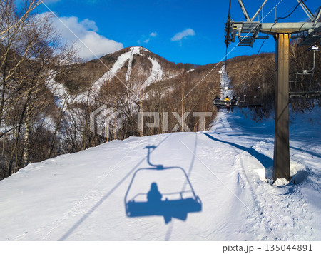 冬のスキー場リフトから望む雪景色と雪面に落ちたスノーボーダーのシルエット (群馬県、川場) 135044891