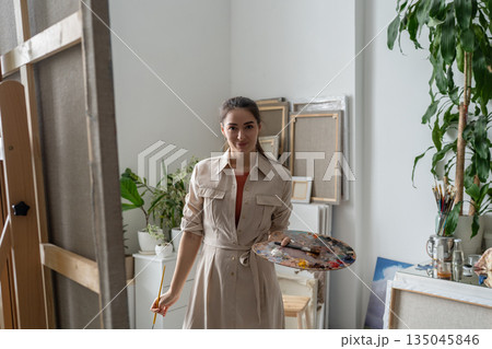 Confident cheerful female artist painting picture at creative home workshop, art hobby therapy. Confident cheerful female artist painting picture at creative home workshop, art hobby therapy. 135045846