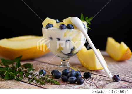 Summer vitamin cream yogurt with melon blueberries on a wooden Summer vitamin cream yogurt with melon blueberries on a wooden 135046054