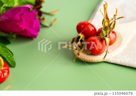harvest of red rose hips on a green background harvest of red rose hips on a green background 135046079
