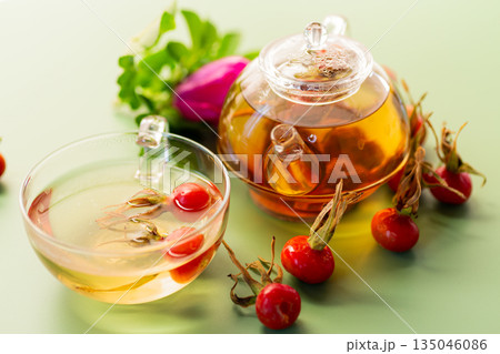 hot natural tea and rose hips on a green background hot natural tea and rose hips on a green background 135046086