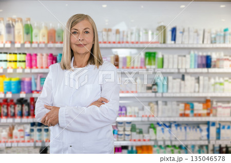 Positive and smiling mature woman in lab coat at the pharmacy 135046578
