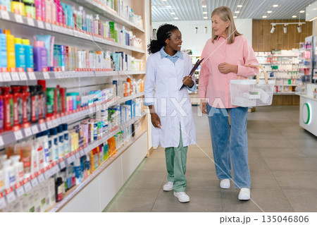 Female customer talking to a drug store assistant and both looking involved 135046806