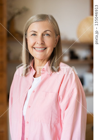 Mature woman standing in kitchen area with friendly smile Mature woman standing in kitchen area with friendly smile 135046913