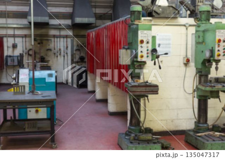Two green drill presses are standing in flat design workshop with red lockers, workbench, ducts 135047317