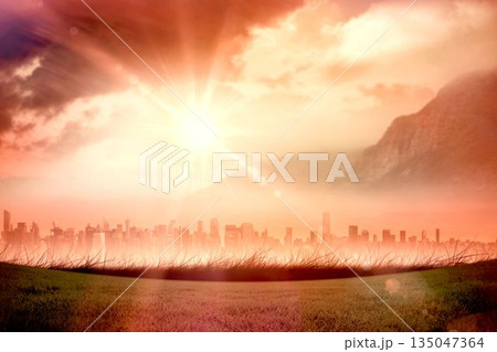 Flat design sun is radiating over grass field with modern skyline, misty mountain and tinted clouds 135047364