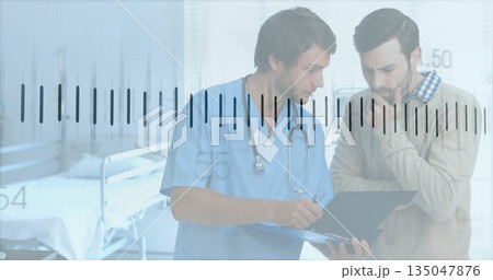 Reviewing doctor in blue scrubs consulting patient in exam room, with clipboard and stethoscope 135047876
