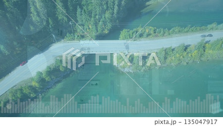 Driving cars traversing road on bridge over turquoise river in mountain forest, with chart overlays 135047917