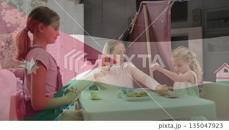 Playing tea mother and daughters at home under play tent lights, with toy tea set, cookies Playing tea mother and daughters at home under play tent lights, with toy tea set, cookies 135047923