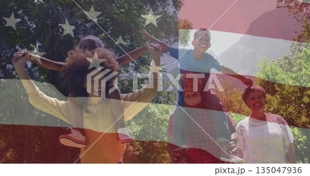 Walking family carrying children on shoulders in sunlit forested park with American flag overlay 135047936