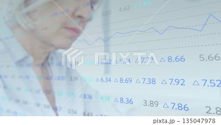 Senior analyst examining financial data overlay, blue line graph, delta symbols at desk Senior analyst examining financial data overlay, blue line graph, delta symbols at desk 135047978